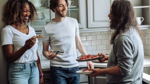 people talking and snacking in a kitchen