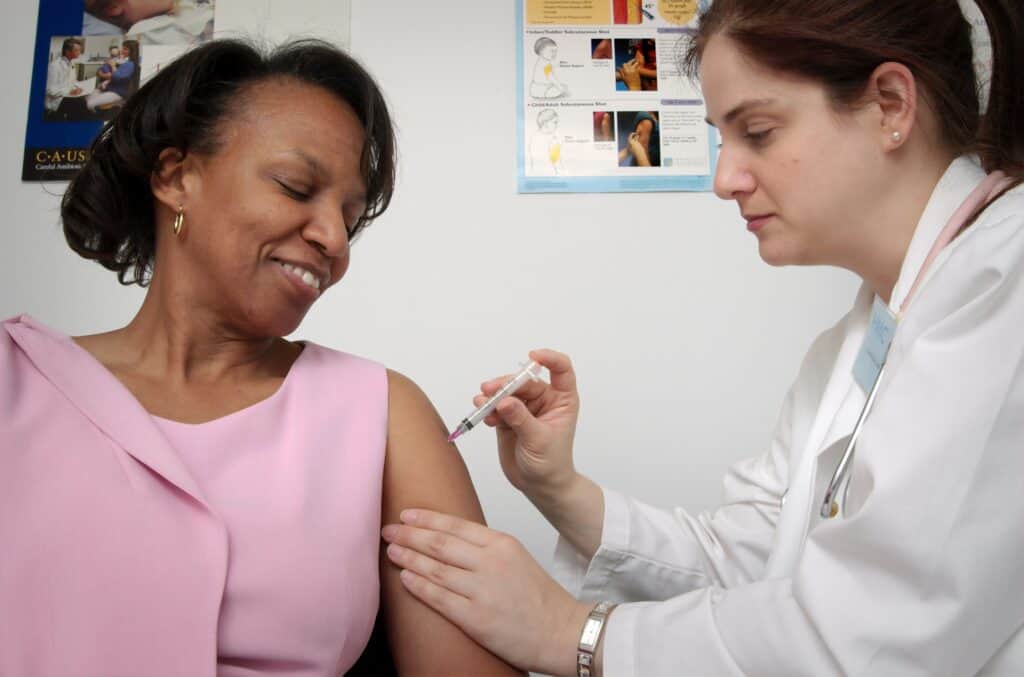 Woman receiving her Flu shot from a healthcare worker