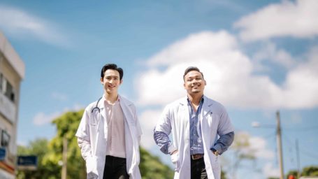 2 asian chinese and malay doctor outdoor walking toward hospital with their medical coat